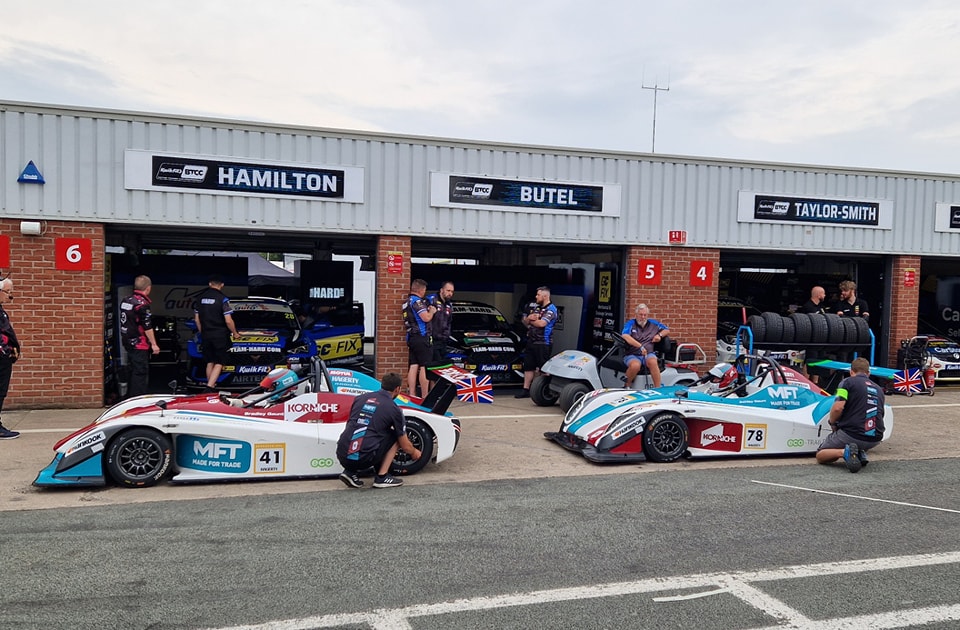 A lineup of SR1 Racing Cars with Made For Trade and Korniche Branding, parked in front of a garage, ready for the Oulton Park race.