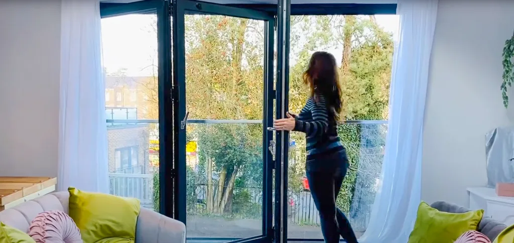 Georgina Burnett opening Korniche Bi-fold Doors in living room.