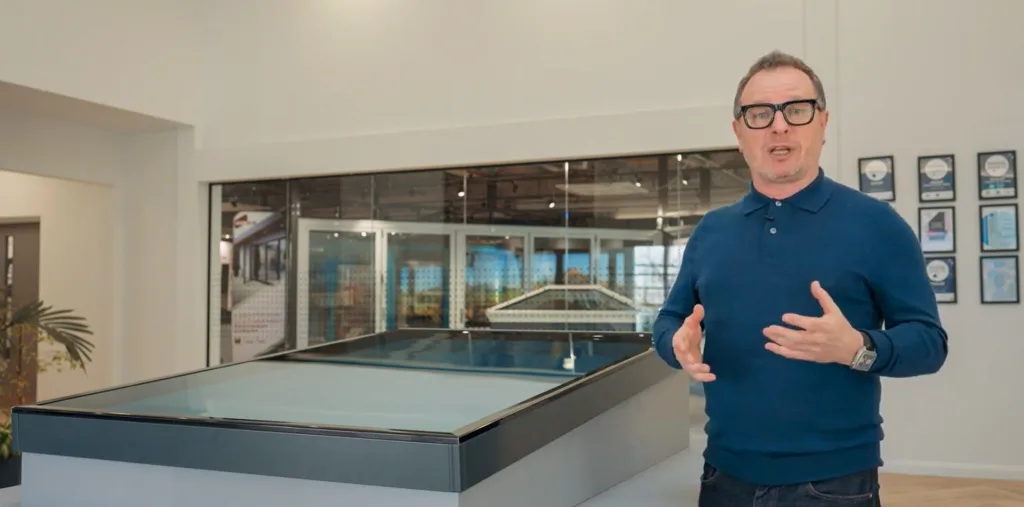 Korniche Brand Ambassador Mark Millar stands beside a Korniche Roof Lantern, showcasing its sleek design and ease of installation.