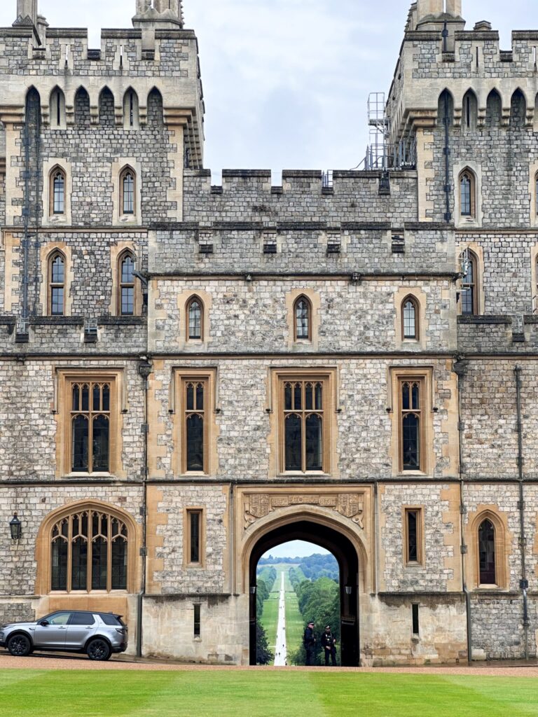 Windsor Castle seen through an archway with The Long Walk leading into the distance